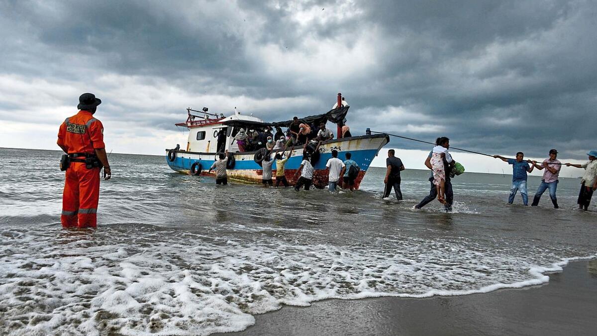 Fishermen helping Rohingya onto the beach at Lancok village in North Aceh Regency. AFP