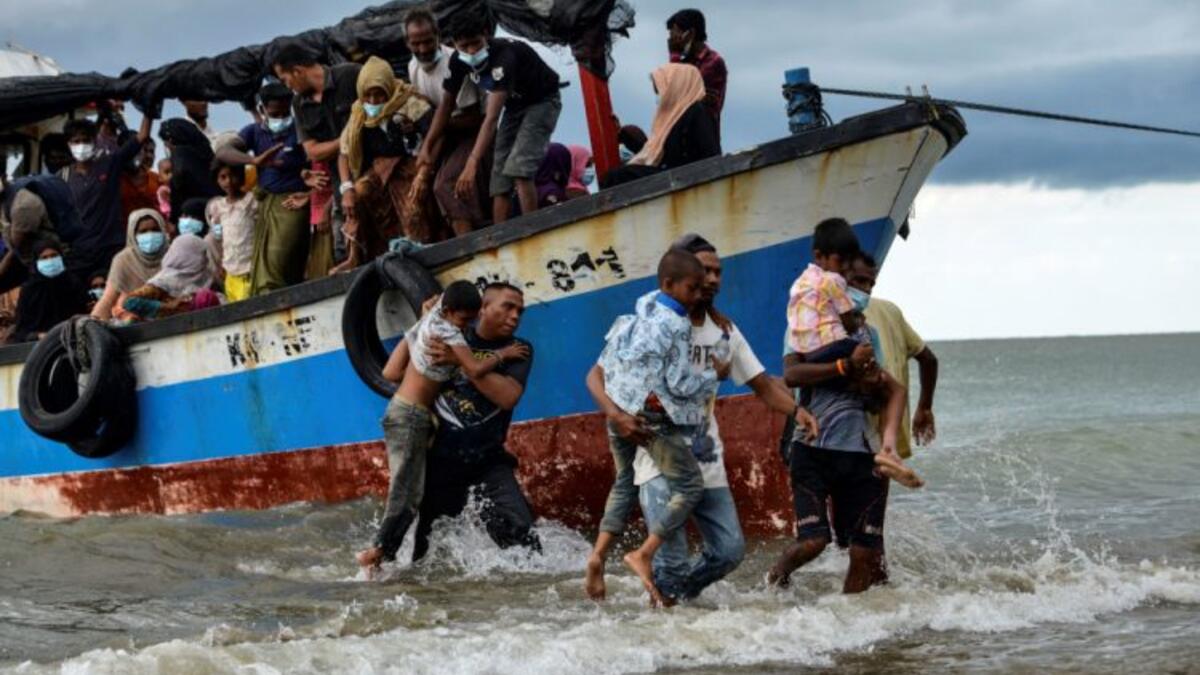 Acehnesse fishermen help evacuate Rohingya children from Myanmar onto the shorelines of Lancok village, in Indonesia's North Aceh Regency on June 25, 2020. - Nearly 100 Rohingya from Myanmar, including 30 children, have been rescued from a rickety wooden boat off the coast of Indonesia's Sumatra island, a maritime official said. (Photo by CHAIDEER MAHYUDDIN / AFP)