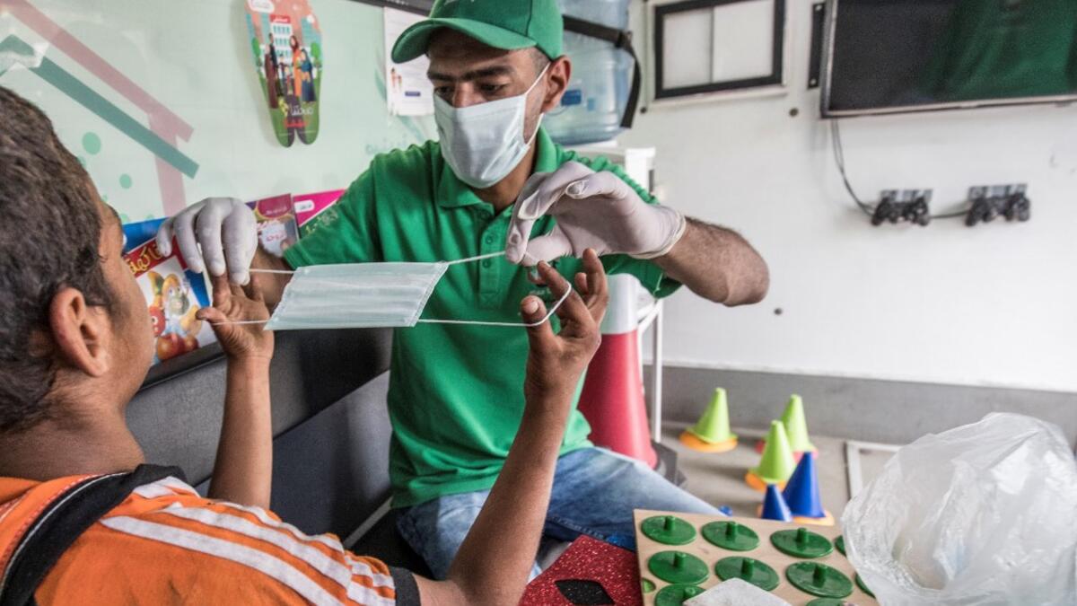 A social worker shows a homeless child the proper way to use a face mask inside one of the mobile units run by the Egyptian authorities and used as part of the "Atfal bala ma'wa" (Children without a home) social program, in the capital Cairo's Abbasia district on June 22, 2020. Khaled DESOUKI / AFP