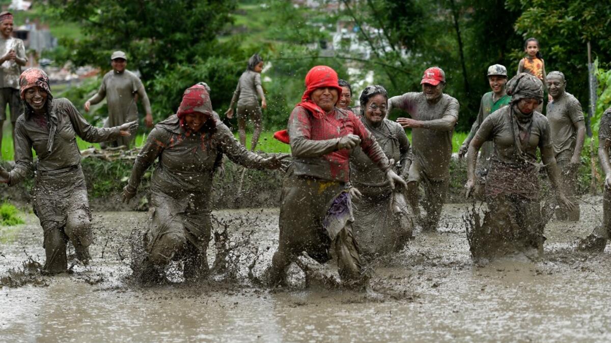 Mud-covered farmers play in a rice paddy field during "National Paddy Day", which marks the start of the annual rice planting season, in Tokha village on the outskirts of Kathmandu on June 29, 2020. PRAKASH MATHEMA / AFP