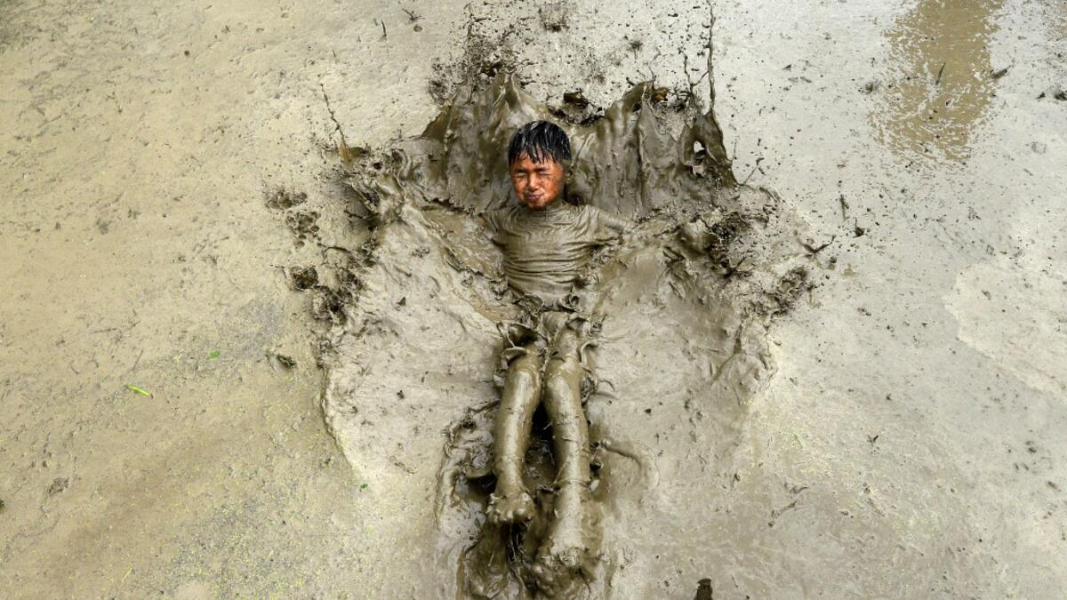 A boy plays in a rice paddy field during "National Paddy Day", which marks the start of the annual rice planting season, in Tokha village on the outskirts of Kathmandu on June 29, 2020. Splashing mud and drinking local rice beer, Nepali farmers this week celebrated National Paddy Day to mark the beginning of the rice-planting season, despite some coronavirus lockdown measures still in place. Traditional farming songs and laughter echoed in the air as farmers waded into waterlogged fields to sow green paddy.