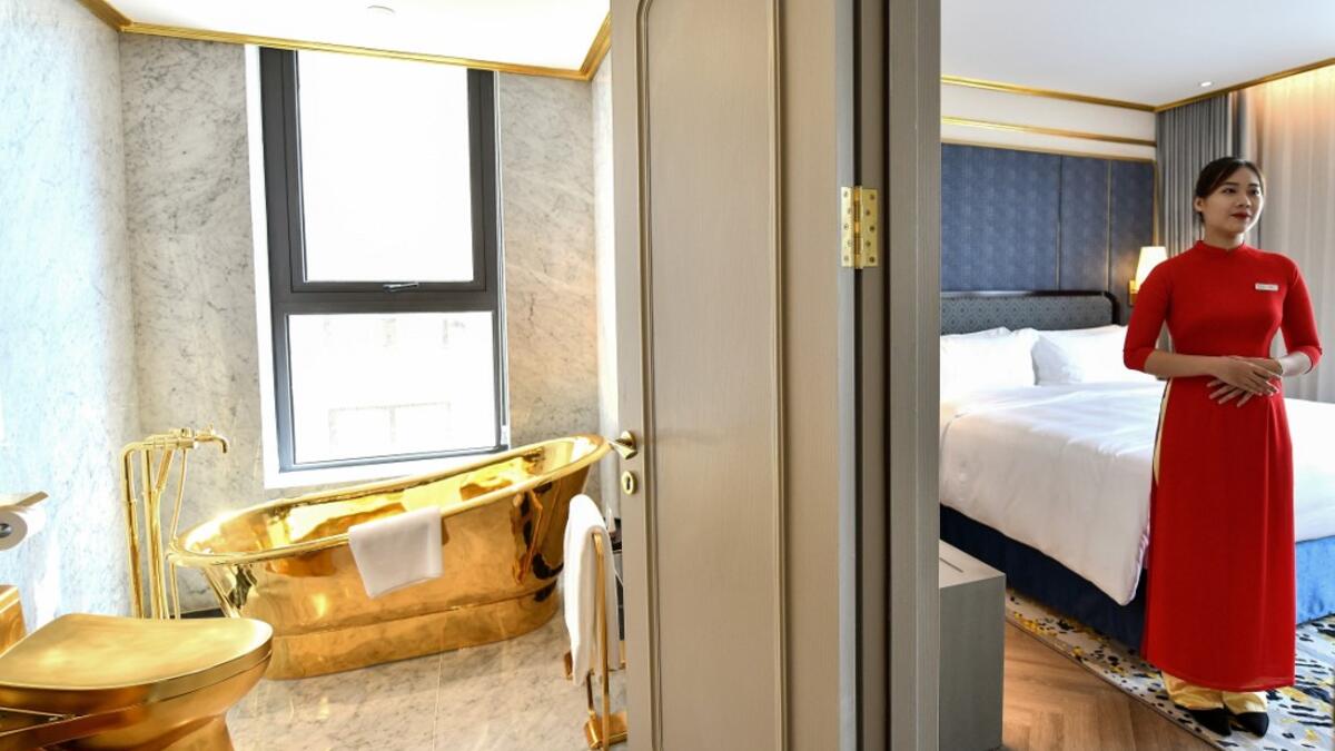 A staff member poses for a photograph inside the 1,000 USD per night executive two bedroom suite of the newly-inaugurated Dolce Hanoi Golden Lake hotel, the world's first gold-plated hotel, in Hanoi on July 2, 2020. Manan VATSYAYANA / AFP