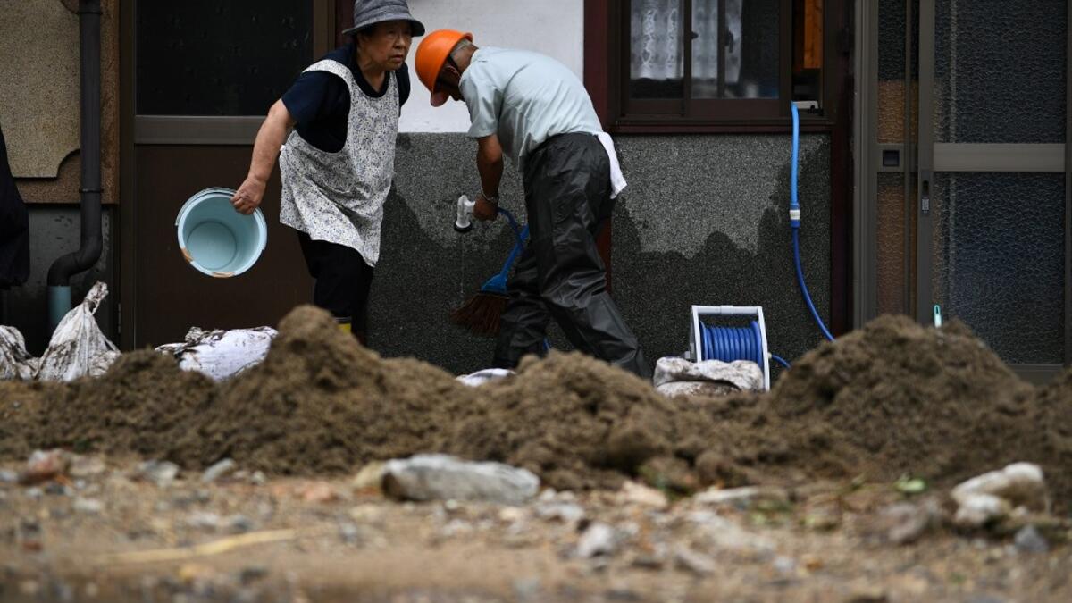 People clear debris and mud outside their home following heavy rains and flooding in the village of Gero, Gifu prefecture on July 9, 2020. Japanese emergency services and troops were scrambling to reach thousands of homes cut off by devastating flooding and landslides that have killed dozens and caused widespread damage. Philip FONG / AFP