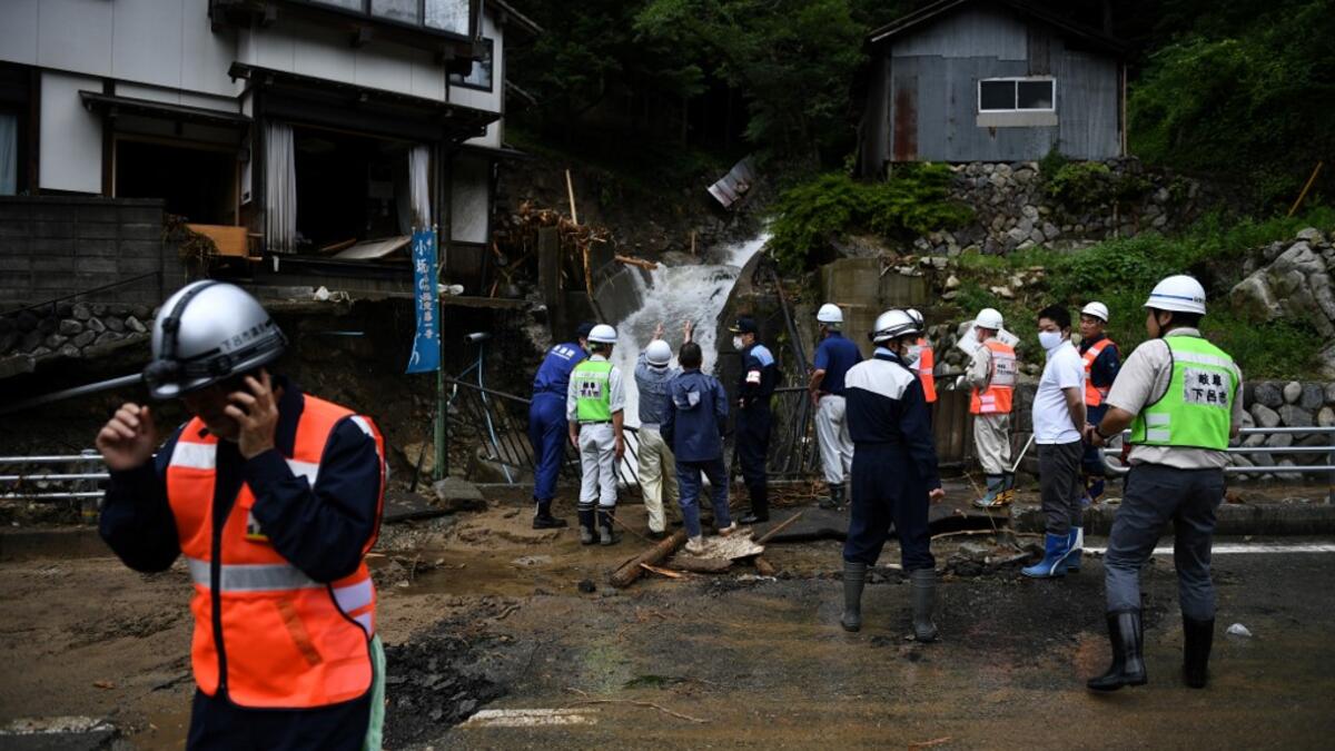 Government officials look at a damaged home following heavy rains and flooding in the village of Gero, Gifu prefecture on July 9, 2020. Japanese emergency services and troops were scrambling to reach thousands of homes cut off by devastating flooding and landslides that have killed dozens and caused widespread damage. Philip FONG / AFP