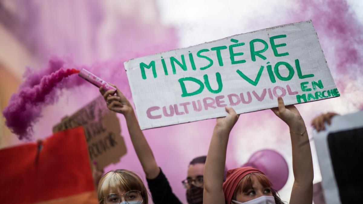 A protester holds a sign reading "Ministry of rape" as another lights a pink flare during a demonstration called by feminist movements in Nantes, western France, on July 10, 2020, to denounce the nomination of French Interior Minister, facing rape accusations and French Justice Minister who criticised the #MeToo movement against sexual harassment. LOIC VENANCE / AFP