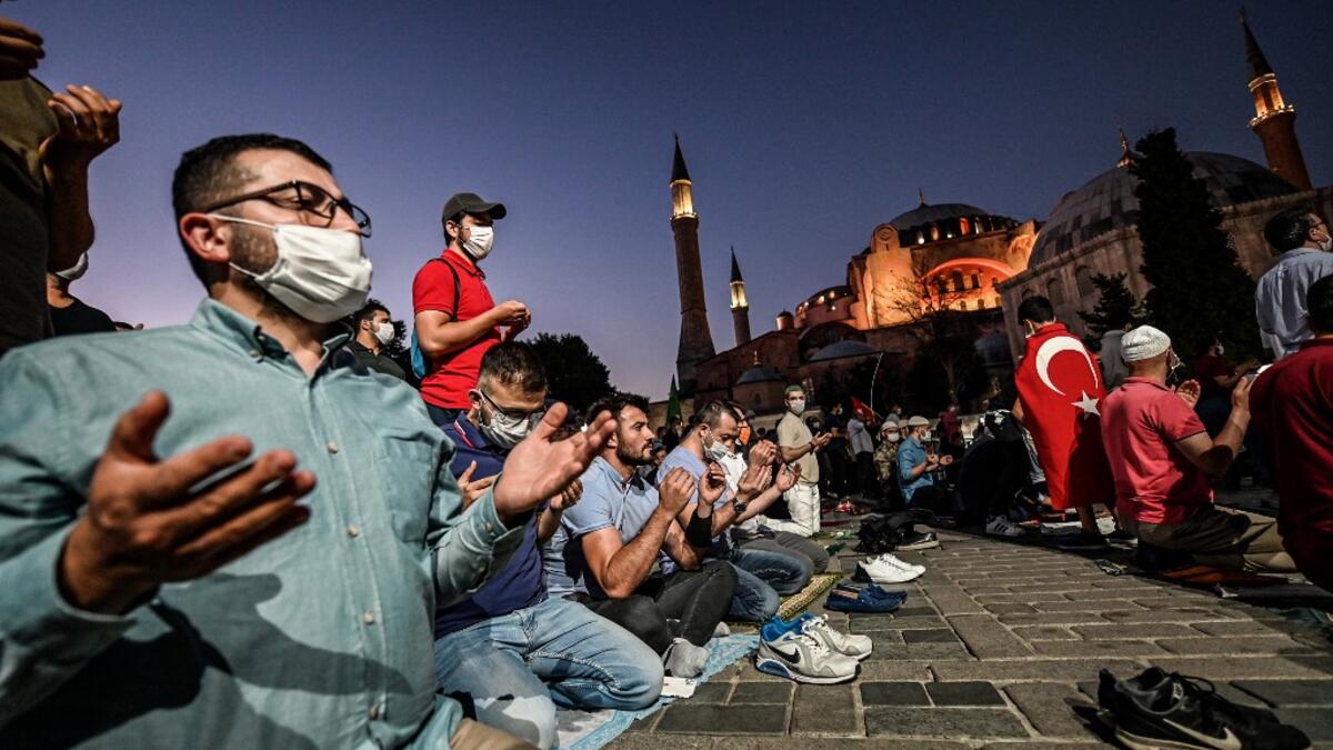 People, some wearing face masks, pray outside the Hagia Sophia museum in Istanbul on July 10, 2020 as they gather to celebrate after a top Turkish court revoked the sixth-century Hagia Sophia's status as a museum, clearing the way for it to be turned back into a mosque. The Council of State, the country's highest administrative court which on July 2 debated a case brought by a Turkish NGO, cancelled a 1934 cabinet decision and ruled the UNESCO World Heritage site would be reopened to Muslim worshipping. The