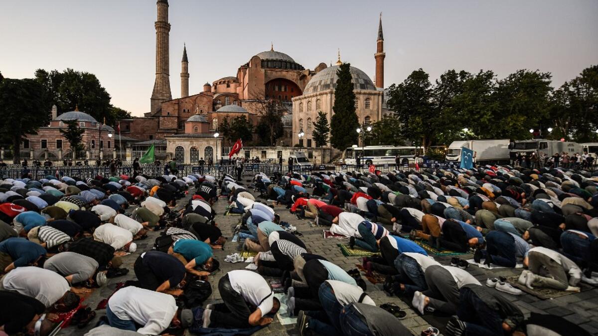People, some wearing face masks, pray outside the Hagia Sophia museum in Istanbul on July 10, 2020 as they gather to celebrate after a top Turkish court revoked the sixth-century Hagia Sophia's status as a museum, clearing the way for it to be turned back into a mosque. The Council of State, the country's highest administrative court which on July 2 debated a case brought by a Turkish NGO, cancelled a 1934 cabinet decision and ruled the UNESCO World Heritage site would be reopened to Muslim worshipping. The