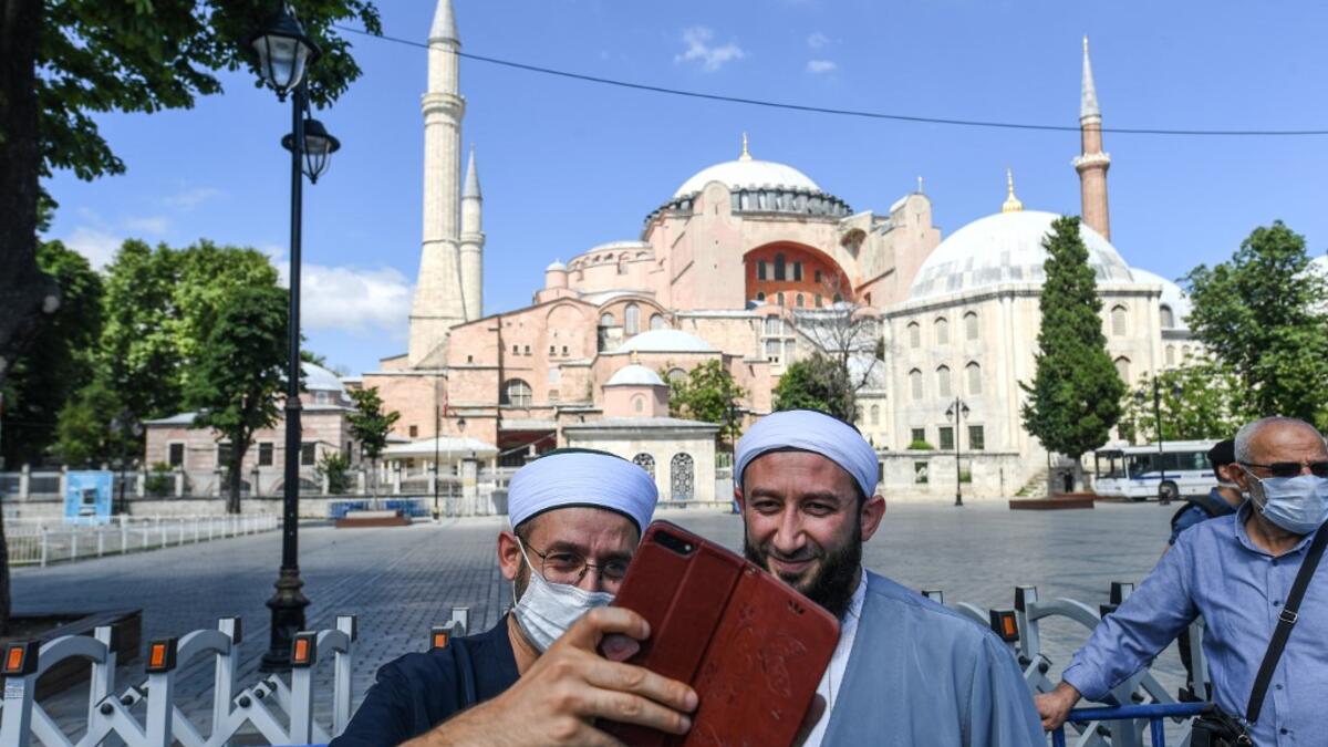 Two men take a selfie picture in front of Hagia Sophia on July 11, 2020 in Istanbul, a day after a top Turkish court revoked the sixth-century Hagia Sophia's status as a museum, clearing the way for it to be turned back into a mosque. The World Council of Churches, which represents 350 Christian churches, said on July 11 it wrote to Turkey's President expressing "grief and dismay" over his decision to turn the Hagia Sophia back into a mosque. Ozan KOSE / AFP