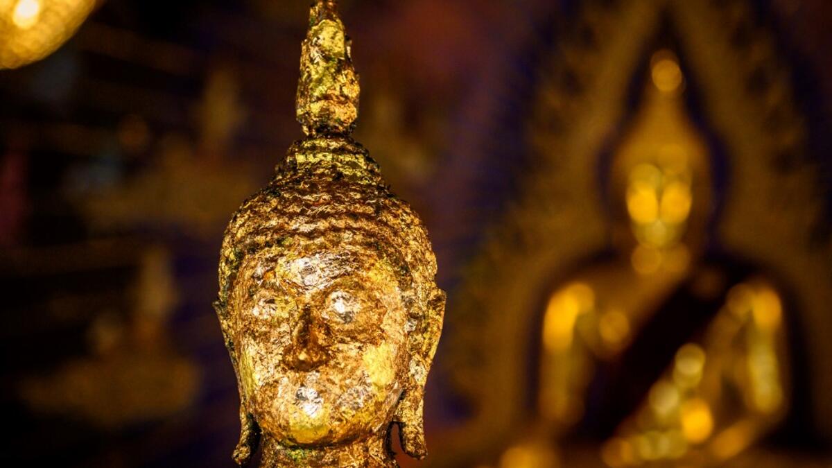 This photograph taken on July 14, 2020 shows Buddha statues inside the Wat Pariwat Buddhist temple in Bangkok. Wat Pariwat, also known as "the David Beckham Temple", is decorated with statues of superheroes and comic characters as well as mythical and imaginary creatures. A golden-plated sculpture of the English football player holding the base of a Buddha statue in one of the buildings gives the temple its nickname. Mladen ANTONOV / AFP