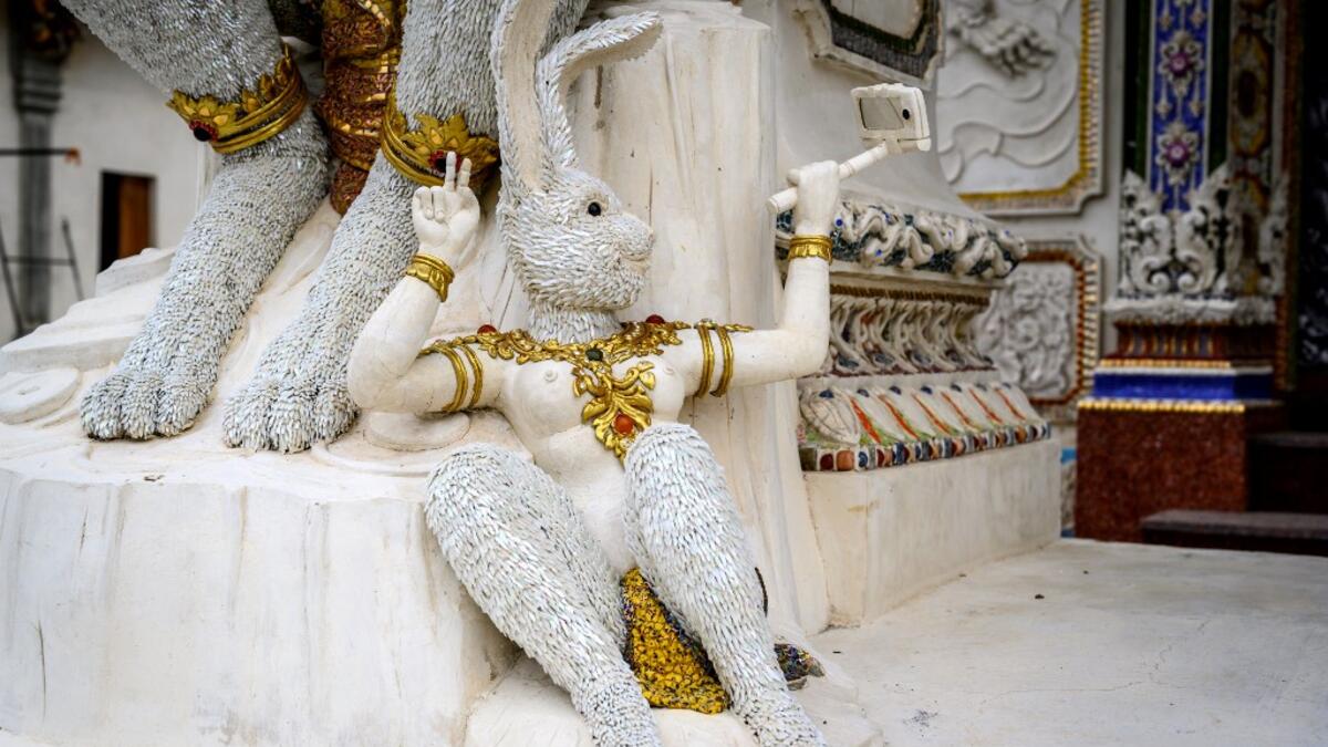 This photograph taken on July 14, 2020 shows a statue of an imaginary rabbit-like creature taking a selfie outside the Wat Pariwat Buddhist temple in Bangkok. Wat Pariwat, also known as "the David Beckham Temple", is decorated with statues of superheroes and comic characters as well as mythical and imaginary creatures. A golden-plated sculpture of the English football player holding the base of a Buddha statue in one of the buildings gives the temple its nickname. Mladen ANTONOV / AFP