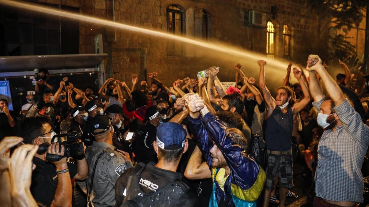 Journalists film as Israeli police spray protesters (clad in masks due to the COVID-19 coronavirus pandemic) with water cannon during an anti-government demonstration in Jerusalem, on July 18, 2020. Ahmad GHARABLI / AFP