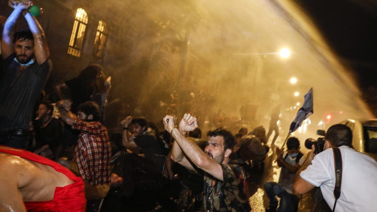 Israeli police spray protesters (clad in masks due to the COVID-19 coronavirus pandemic) with water cannon during an anti-government demonstration in Jerusalem, on July 18, 2020. Ahmad GHARABLI / AFP