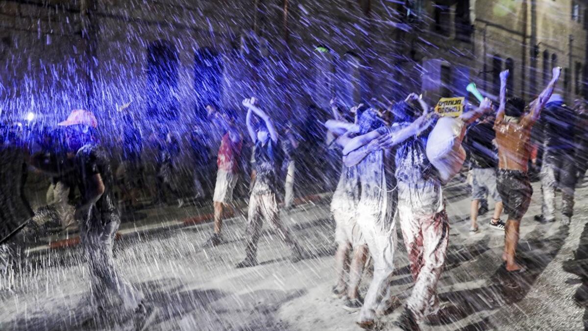 Israeli police spray protesters (clad in masks due to the COVID-19 coronavirus pandemic) with water cannon during an anti-government demonstration in Jerusalem, on July 18, 2020. Ahmad GHARABLI / AFP