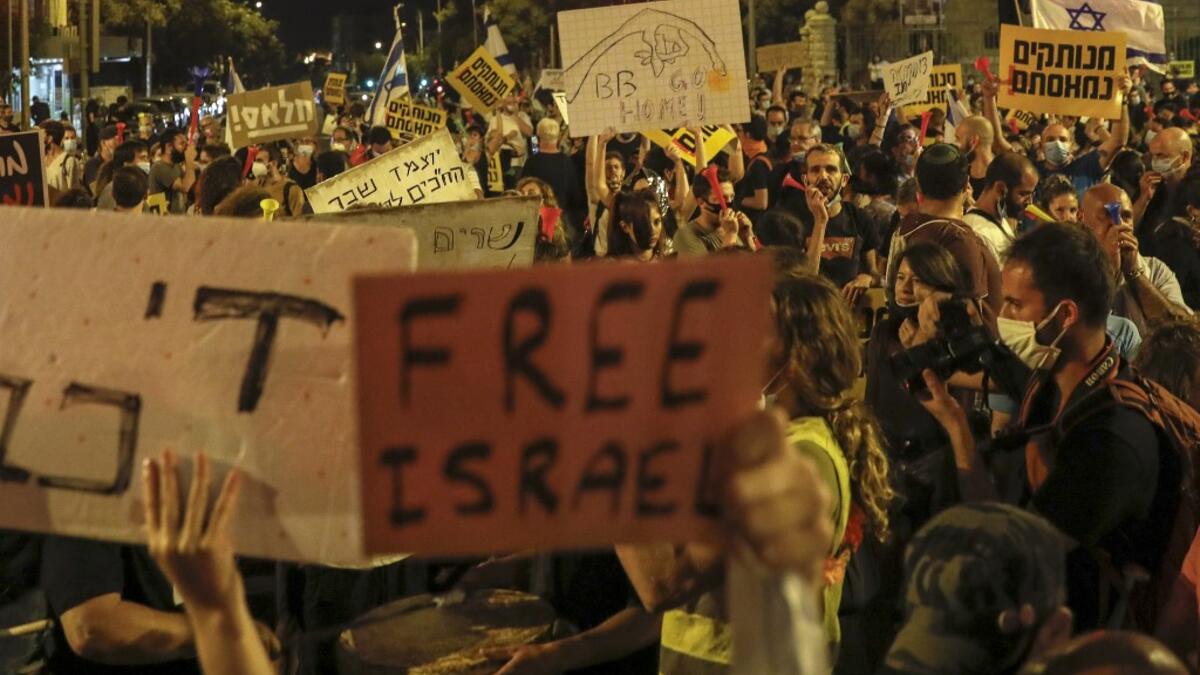 Israeli demonstrators lift placards during a rally against Prime Minister Benjamin Netanyahu outside his official residence in Jerusalem, on July 18, 2020, amid the coronavirus pandemic. Israeli police fired water cannons to disperse anti-government protests attended by thousands on Saturday, as public anger mounts over the handling of the coronavirus crisis.
