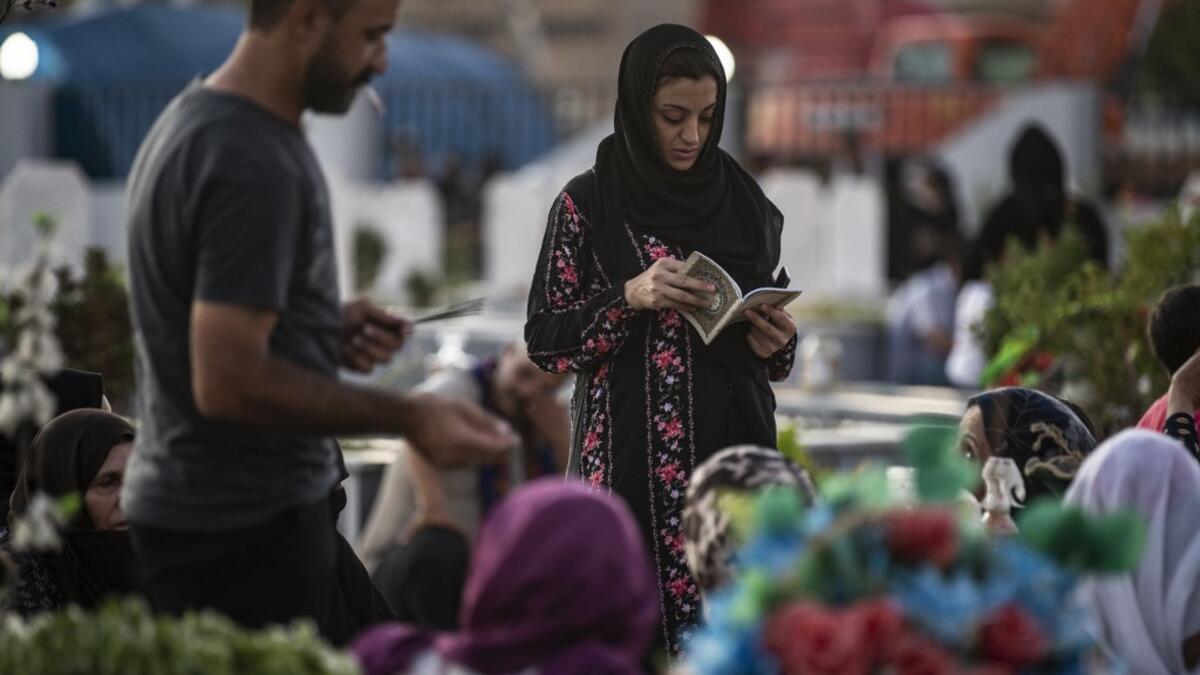 Relatives of a slain Kurdish fighter with the Syrian Democratic Forces (SDF), visit his tomb at a cemetery in the Kurdish-majority city of Qamishli of Syria's northeastern Hasakeh province, on the eve of the holy Muslim Feast of Sacrifice or Eid al-Adha on July 30, 2020. Delil SOULEIMAN / AFP
