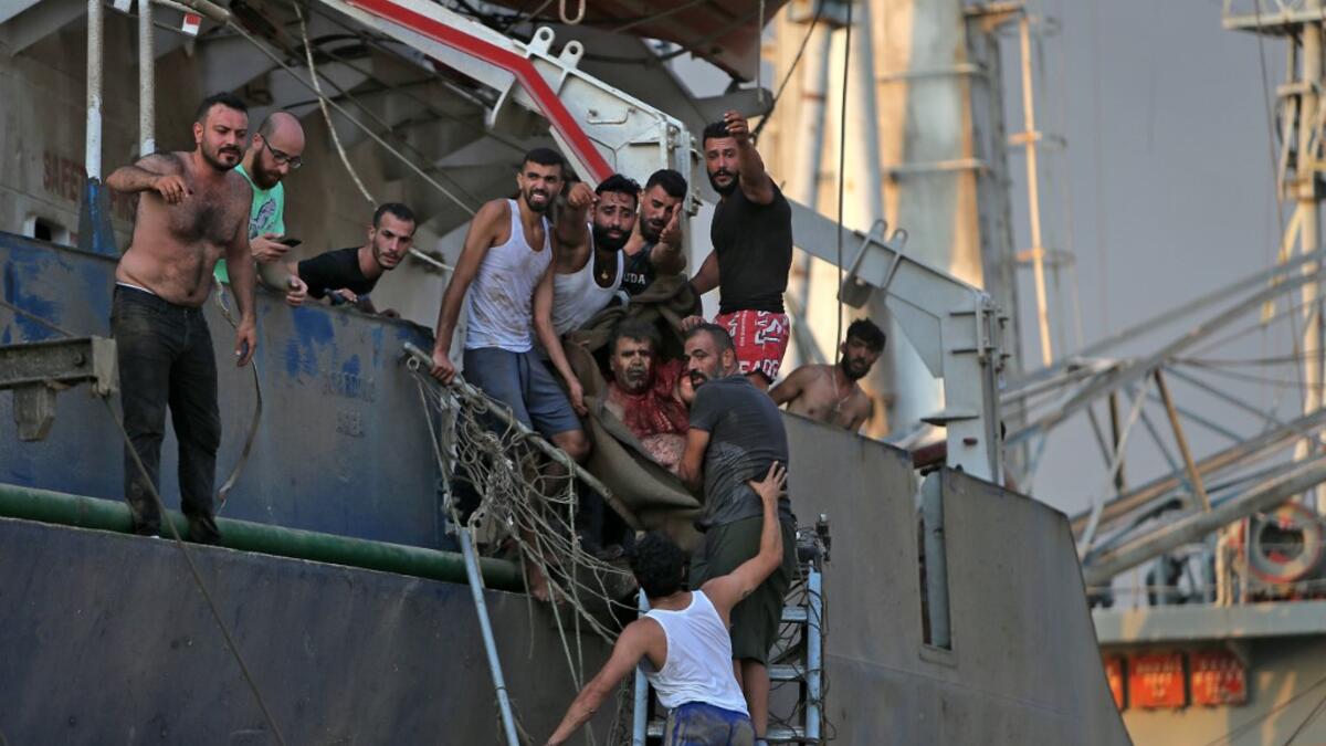 A man is evacuated from a boat following of an explosion near the port in the Lebanese capital Beirut on August 4, 2020. Two huge explosion rocked the Lebanese capital Beirut, wounding dozens of people, shaking buildings and sending huge plumes of smoke billowing into the sky. Lebanese media carried images of people trapped under rubble, some bloodied, after the massive explosions, the cause of which was not immediately known.  STR / AFP