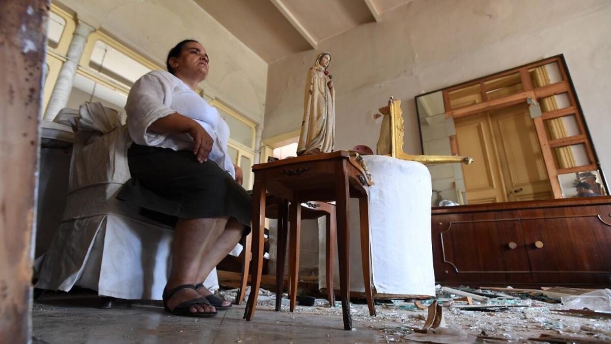 A woman sits next to a statue of Virgin Mary in her damaged house in the Lebanese capital Beirut on August 6, 2020, two days after a massive explosion shook the Lebanese capital. The blast, which appeared to have been caused by a fire igniting 2,750 tonnes of ammonium nitrate left unsecured in a warehouse, was felt as far away as Cyprus, some 150 miles (240 kilometres) to the northwest. The scale of the destruction was such that the Lebanese capital resembled the scene of an earthquake, with thousands of pe