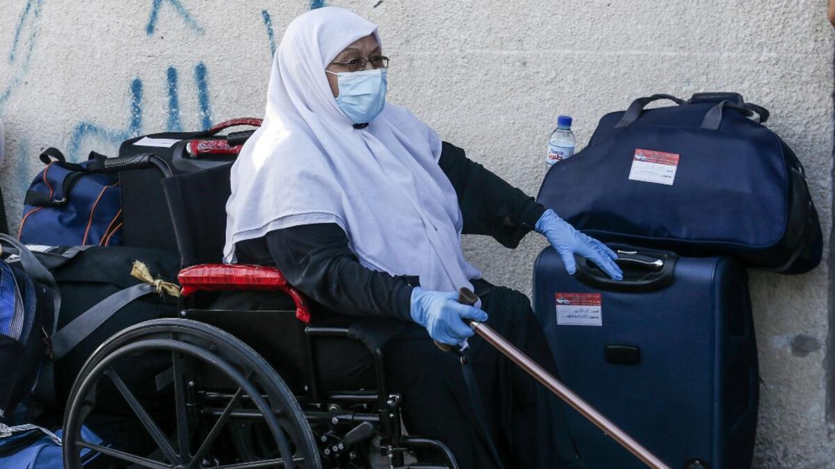 A Palestinian woman waits next to her luggage to leave Rafah border crossing with Egypt after months of closure due to the coronavirus pandemic in the southern Gaza Strip, on August 11, 2020. SAID KHATIB / AFP