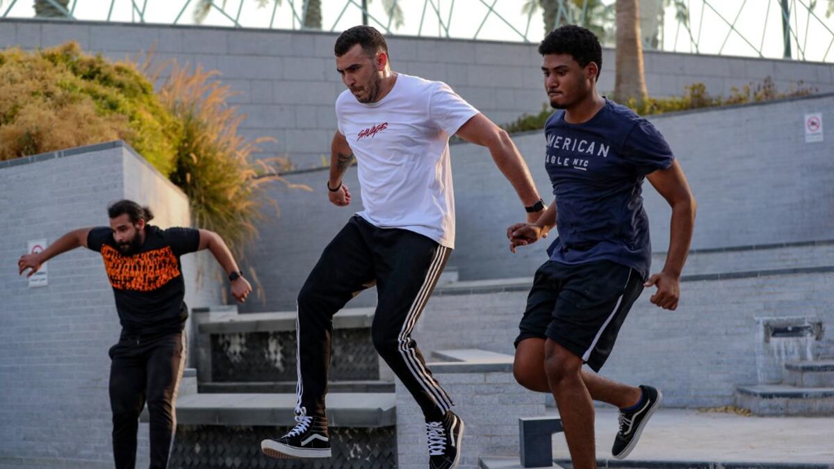 Hamzar Mekkaoui (L) , Achref Bejaoui (C) and a friend perform parkour, a sport that originated in France in the 1990s, which involves getting around urban obstacles with a fast-paced mix of jumping, vaulting, running and rolling, in the Qatari capital Doha, on August 11, 2020. Parkour, also known as free-running, has now found a small but committed following in Qatar despite evening temperatures that hover around 40 degrees Celsius (104 Fahrenheit) in summer and over-zealous security guards unfamiliar with