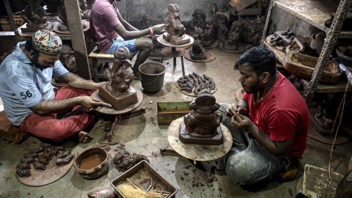 In this picture taken on August 15, 2020, Muslim potter Yusuf Zakaria Galwani (L) along with his staff, work on the idols of elephant headed Hindu god Ganesha at his workshop at Kumbharwada inside the Dharavi slums in Mumbai. After the coronavirus pandemic clobbered his pottery business, a Muslim artisan from India's largest slum turned to a Hindu god to revive his fortunes by making environmentally-friendly Ganesha idols for an upcoming festival. In Mumbai's Dharavi slum, Galwani worked alongside his two b