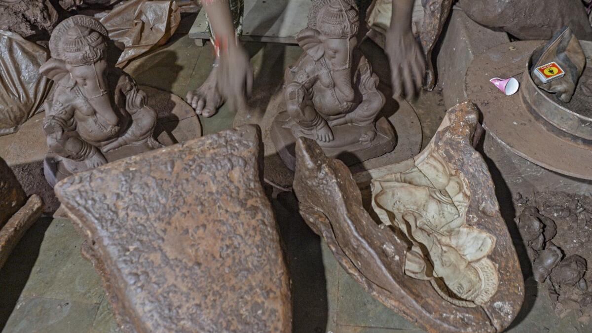 In this picture taken on August 15, 2020, a staff takes out a clay idol of elephant headed Hindu god Ganesha from a mould at Muslim potter Yusuf Zakaria Galwani's workshop at Kumbharwada inside the Dharavi slums in Mumbai. After the coronavirus pandemic clobbered his pottery business, a Muslim artisan from India's largest slum turned to a Hindu god to revive his fortunes by making environmentally-friendly Ganesha idols for an upcoming festival. In Mumbai's Dharavi slum, Galwani worked alongside his two brot