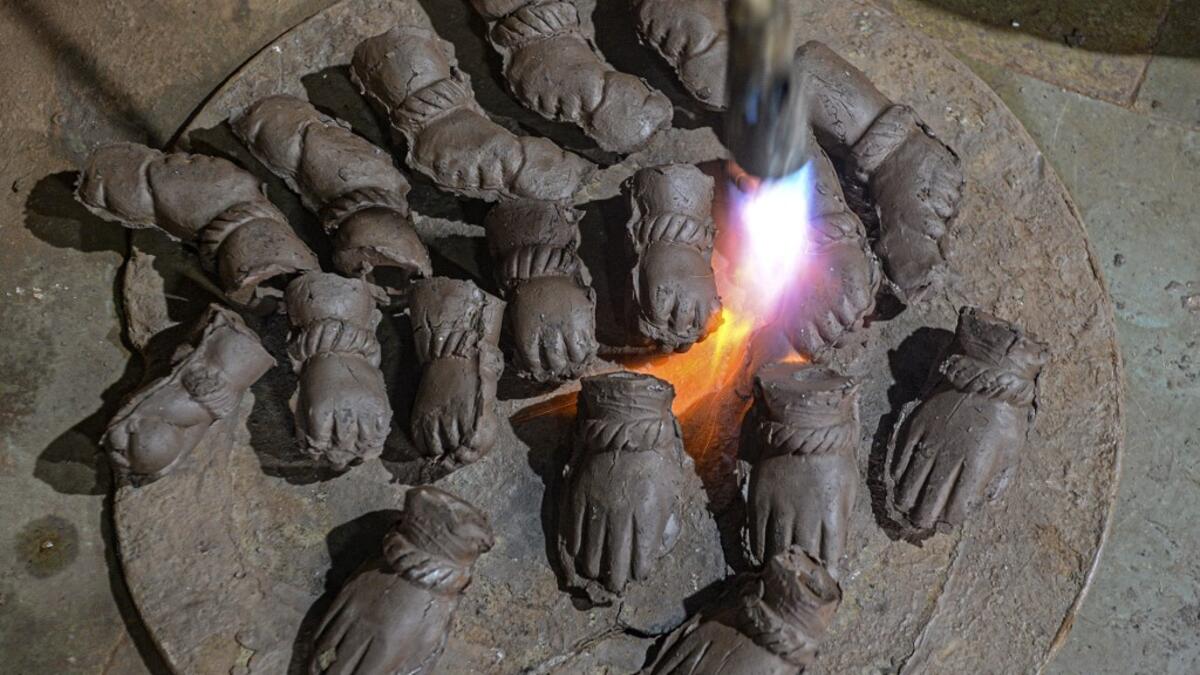 In this picture taken on August 15, 2020, an artisan uses a blowtorch to dry the hands of clay idols of elephant headed Hindu god Ganesha at Muslim potter Yusuf Zakaria Galwani's workshop at Kumbharwada inside the Dharavi slums in Mumbai. After the coronavirus pandemic clobbered his pottery business, a Muslim artisan from India's largest slum turned to a Hindu god to revive his fortunes by making environmentally-friendly Ganesha idols for an upcoming festival. In Mumbai's Dharavi slum, Galwani worked alongs