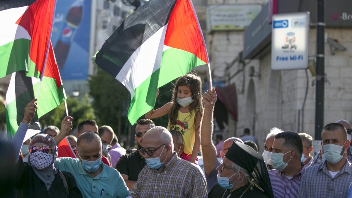Palestinian protesters lift national flags during a demonstration against the Emirati-Israeli agreement, in Ramallah in the occupied West Bank, on August 15, 2020. ABBAS MOMANI / AFP