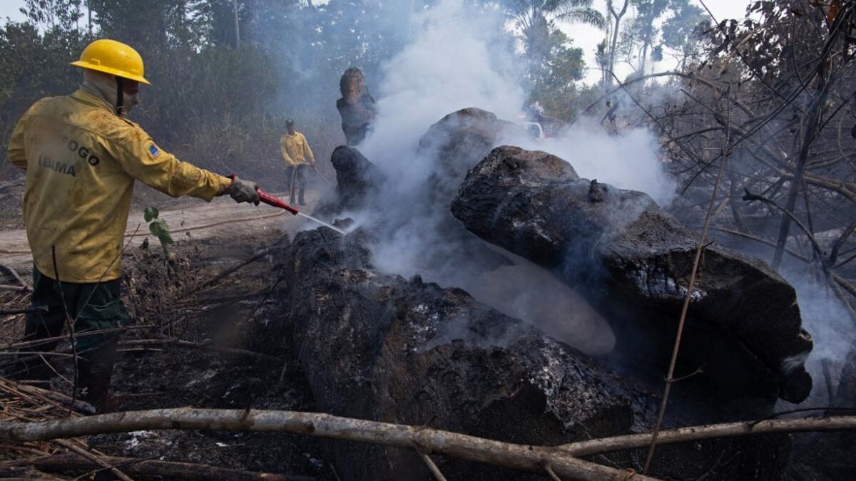A member of fire prevention group PREVFOGO extinguishes a burning area of the Amazon rainforest reserve, south of Novo Progresso in Para state, Brazil, on August 15, 2020. JOÃO LAET / AFP
