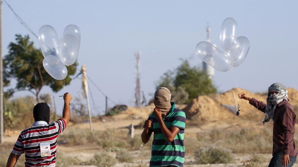 Palestinians prepare incendiary devices attached to inflated condoms to be directed and flown towards Israel, near Rafah along the border between the Gaza Strip and Israel on August 21, 2020. SAID KHATIB / AFP