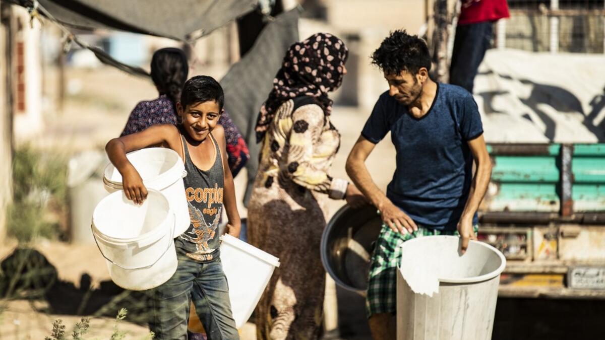 Residents carry plastic buckets to fill up water from cisterns, provided by humanitarian organisations, during a water outage in Syria's northeastern city of Hasakah on August 22, 2020. As coronavirus spreads across northeast Syria, residents in Hasakeh have been caught up in the latest spat between Turkish forces to the north and Syrian Kurds it views as "terrorists". In October last year, Turkish forces occupied a 120-stretch (70-mile) stretch of land inside the Syrian border, including the Alouk power st