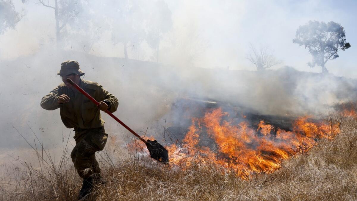 An Israeli soldier battles a blaze in a field close to the southern Israeli kibbutz of Nir Am near the border with the Gaza Strip on August 23, 2020, after it was reportedly set off by incendiary kites flown from the Palestinian enclave. menahem kahana / AFP