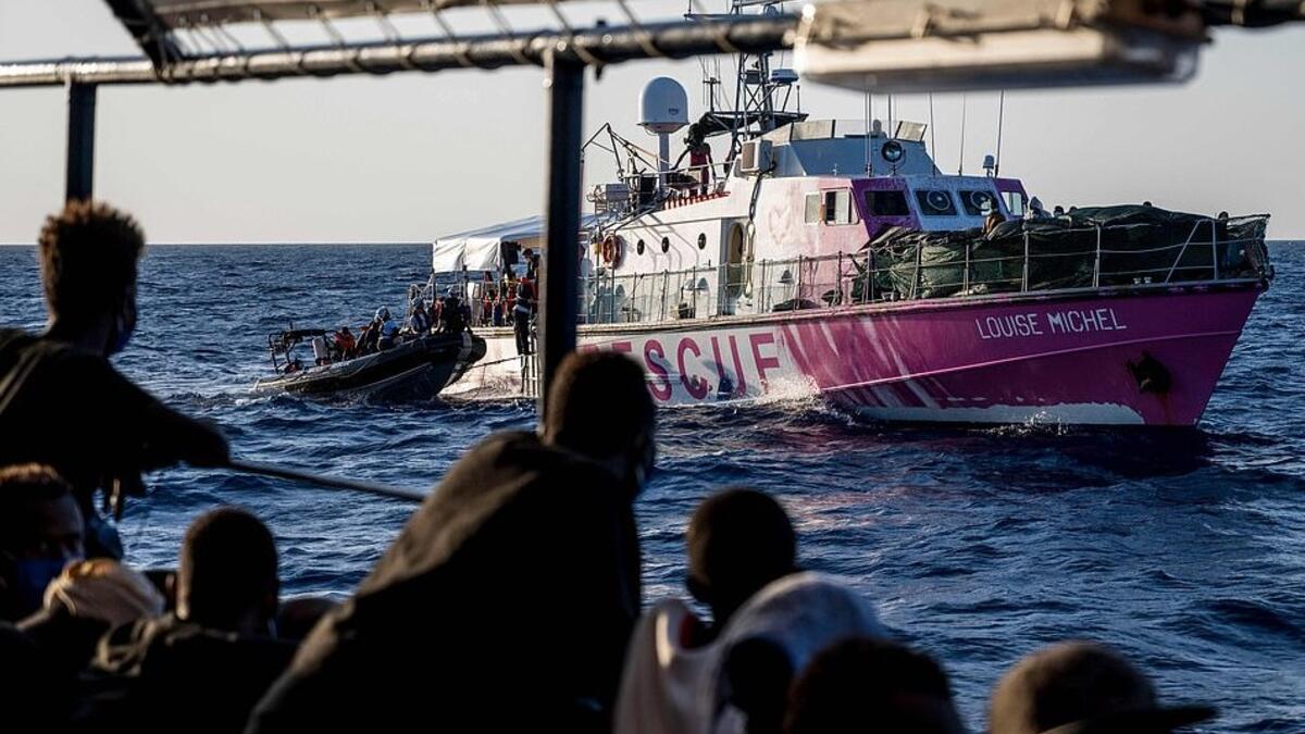 Migrants rescued by Sea-Watch 4 a week ago in the international waters off Libya watch crew members of civil sea rescue ship Sea-Watch 4 on inflatable boats help migrants to get off the rescue ship (AFP)