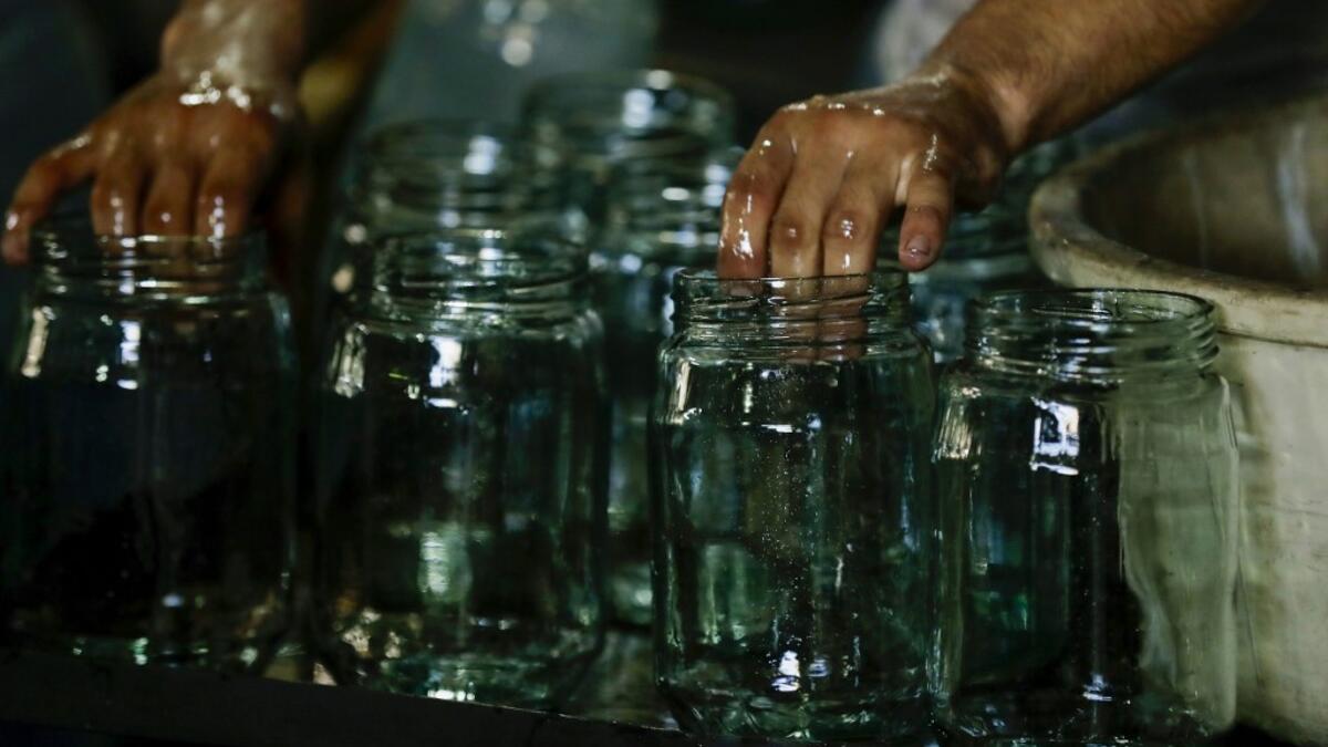 A worker washes jugs at a factory, which is recycling the broken glass as a result of the Beirut explosion, in the northern Lebanese port city of Tripoli on August 25, 2020. The August 4 port explosion ripped through countless glass doors and windows when it laid waste to whole Beirut neighbourhoods, killing at least 190 people and wounding thousands more. Volunteers, non-governmental groups and entrepreneurs salvaged a fraction of the tonnes of broken glass that littered the streets, some of it through rec