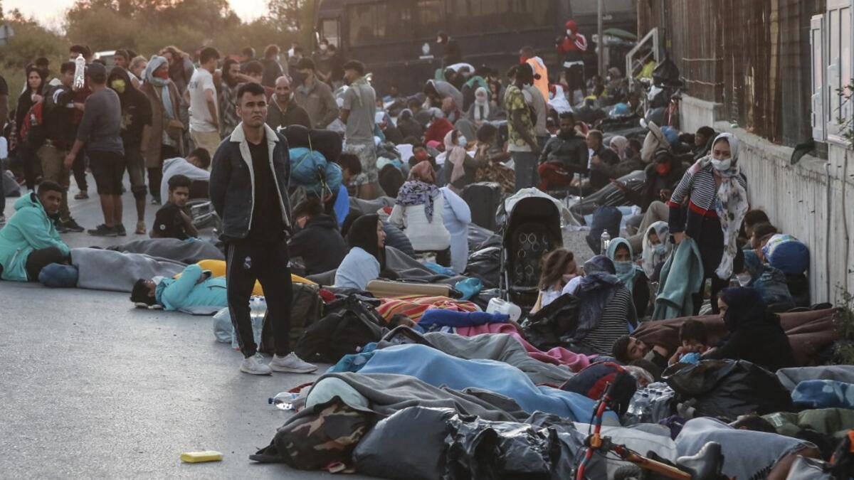 People stand in a street on the island of Lesbos after a major fire broke out in the camp of Moria, on September 9, 2020. Thousands of asylum seekers on the Greek island of Lesbos fled for their lives on September 9, 2020 as a huge fire ripped through the camp of Moria, the country's largest and most notorious migrant facility.