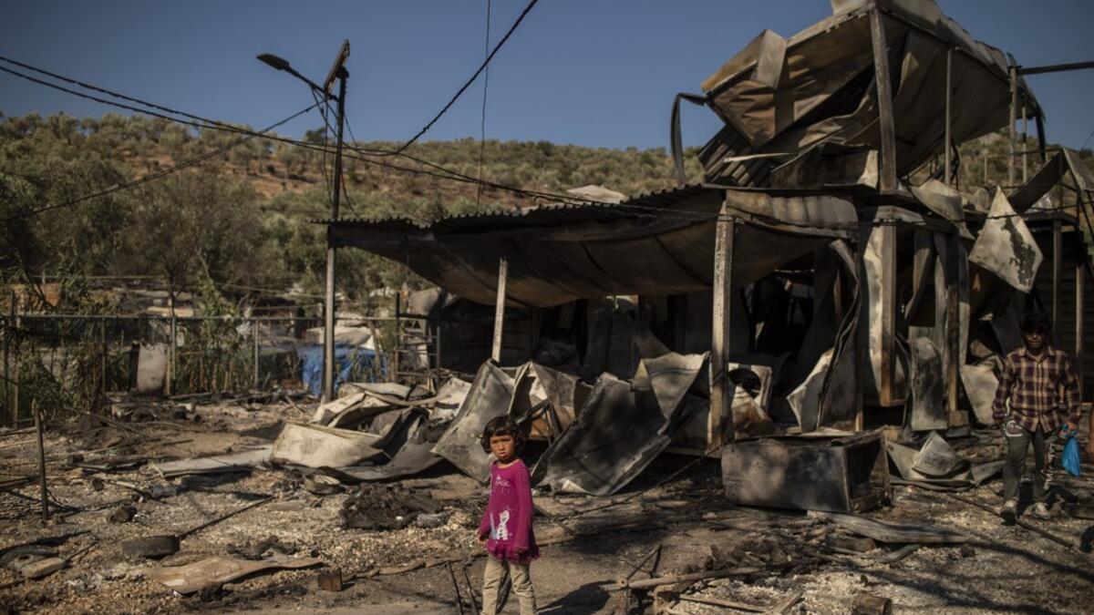 A girl stands amid rubbles in the burnt camp of Moria on the island of Lesbos after a major fire broke out, on September 9, 2020. Thousands of asylum seekers on the Greek island of Lesbos fled for their lives on September 9, 2020 as a huge fire ripped through the camp of Moria, the country's largest and most notorious migrant facility. Over 12,000 men, women and children ran in panic out of containers and tents and into adjoining olive groves and fields as the fire destroyed most of the overcrowded, squalid