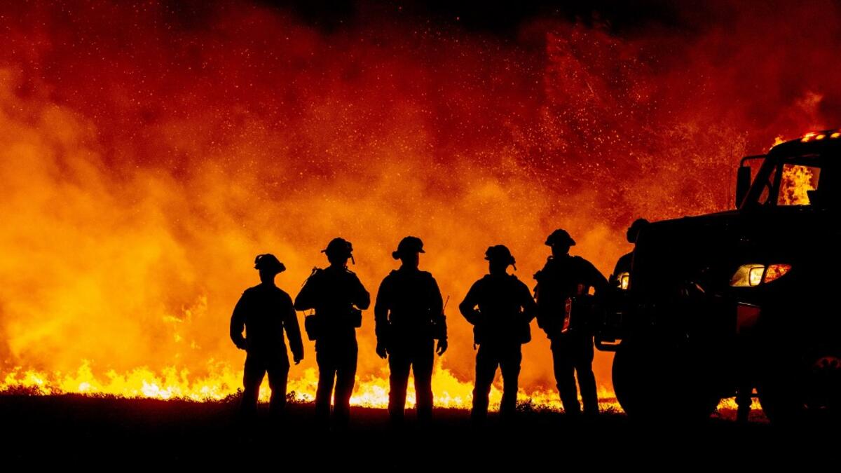 Butte County firefighters watch as flames quickly spread across a road at the Bear fire in Oroville, California on September 9, 2020. Dangerous dry winds whipped up California's record-breaking wildfires and ignited new blazes, as hundreds were evacuated by helicopter and tens of thousands were plunged into darkness by power outages across the western United States. JOSH EDELSON / AFP