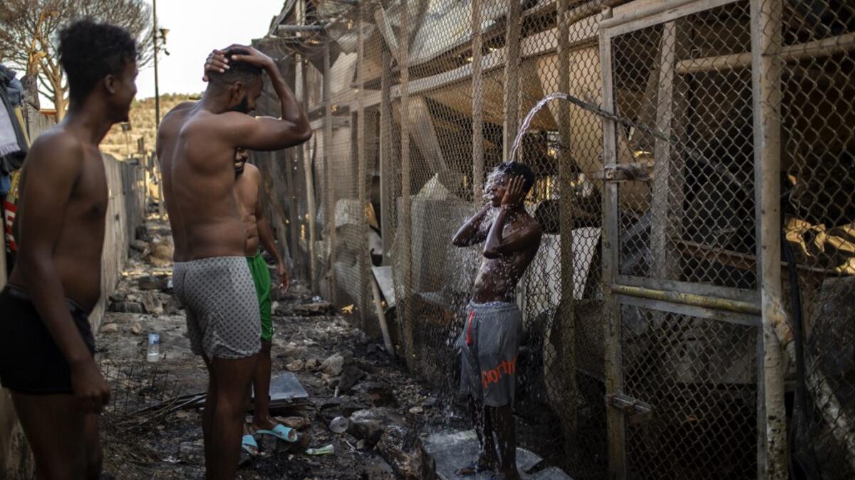 Migrants take shower Children walk in the burnt migrants camp of Moria on the Greek Aegean island of Lesbos on September 9, 2020 after a major fire broke out. Thousands of asylum seekers were left homeless on September 9 after a fire gutted Greece's largest migrant camp on Lesbos, plunging the island into crisis and provoking an outpouring of sympathy from around Europe and calls for reform of the refugee system.