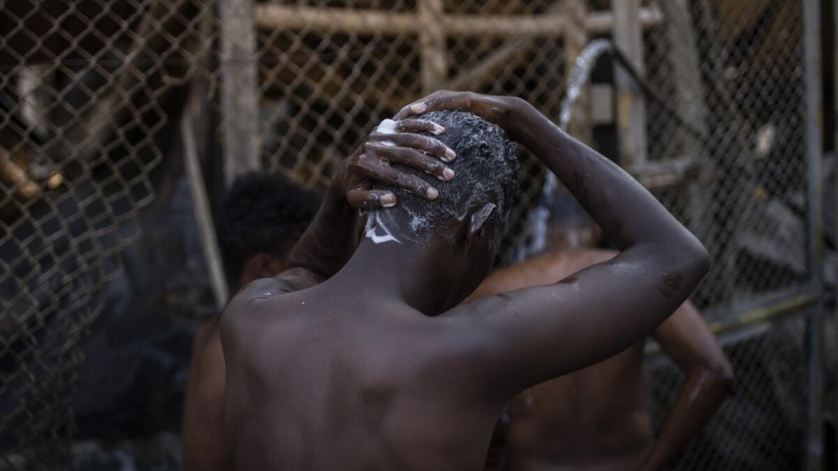 Migrants take shower Children walk in the burnt migrants camp of Moria on the Greek Aegean island of Lesbos on September 9, 2020 after a major fire broke out. Thousands of asylum seekers were left homeless on September 9 after a fire gutted Greece's largest migrant camp on Lesbos, plunging the island into crisis and provoking an outpouring of sympathy from around Europe and calls for reform of the refugee system.