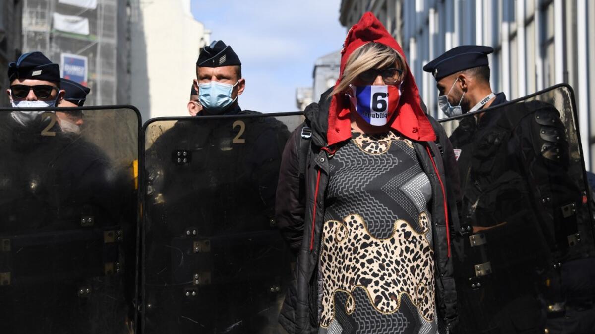 A protester wearing a protective face mask stands in front of riot police officers during a demonstration called by the "yellow vest" (gilets jaunes) movement on September 12, 2020 in Paris. Alain JOCARD / AFP