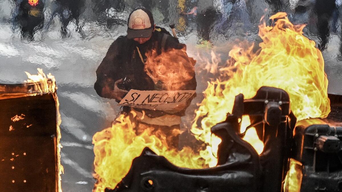 A man stands behind a burning barricade during the fifth straight day of protests against police brutality in Bogota on September 13, 2020. Juan BARRETO / AFP