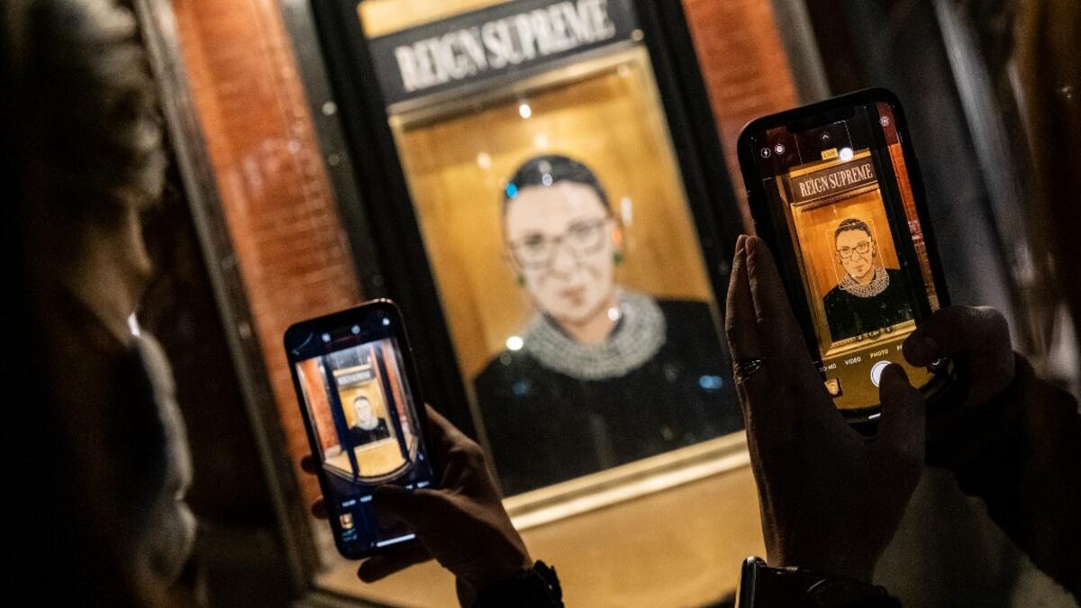 People take a picture of a portrait of Supreme Court Justice Ruth Bader Ginsburg displayed at a storefront on September 19, 2020 in New York, New York. Ginsburg has died at age 87 after a battle with pancreatic cancer. Jeenah Moon/Getty Images/AFP Jeenah Moon / GETTY IMAGES NORTH AMERICA / Getty Images via AFP