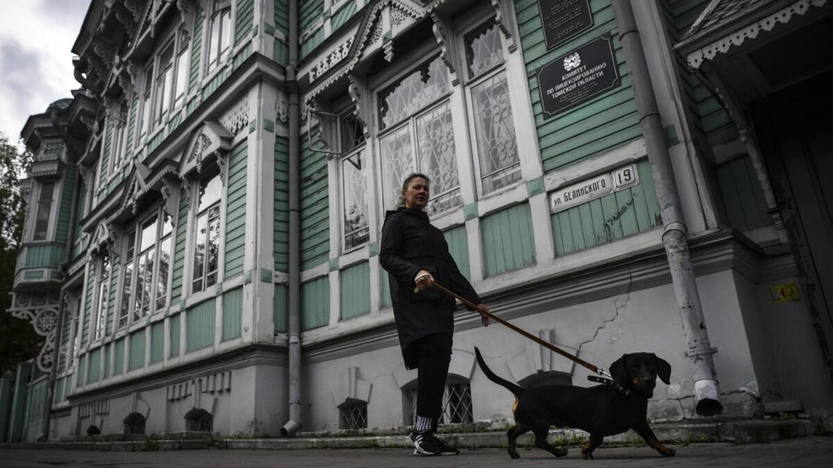 A woman walks a dog past former house of Russian architect Stanislav Khomich, 1904, a traditional wooden house in the Siberian city of Tomsk, on September 8, 2020. Tomsk is considered to be one of the oldest towns in Siberia founded in 1604. Wooden architecture is one of the symbols of the city of Tomsk, its distinctive feature. Today Tomsk is the only city in Siberia where the background wooden buildings have been preserved, reflecting the manor structure of the city streets. Unfortunately, many wooden hou