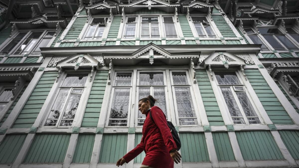 A woman walks past former house of Russian architect Stanislav Khomich, 1904, a traditional wooden house in the Siberian city of Tomsk, on September 8, 2020. Tomsk is considered to be one of the oldest towns in Siberia founded in 1604. Wooden architecture is one of the symbols of the city of Tomsk, its distinctive feature. Today Tomsk is the only city in Siberia where the background wooden buildings have been preserved, reflecting the manor structure of the city streets. Unfortunately, many wooden houses ar