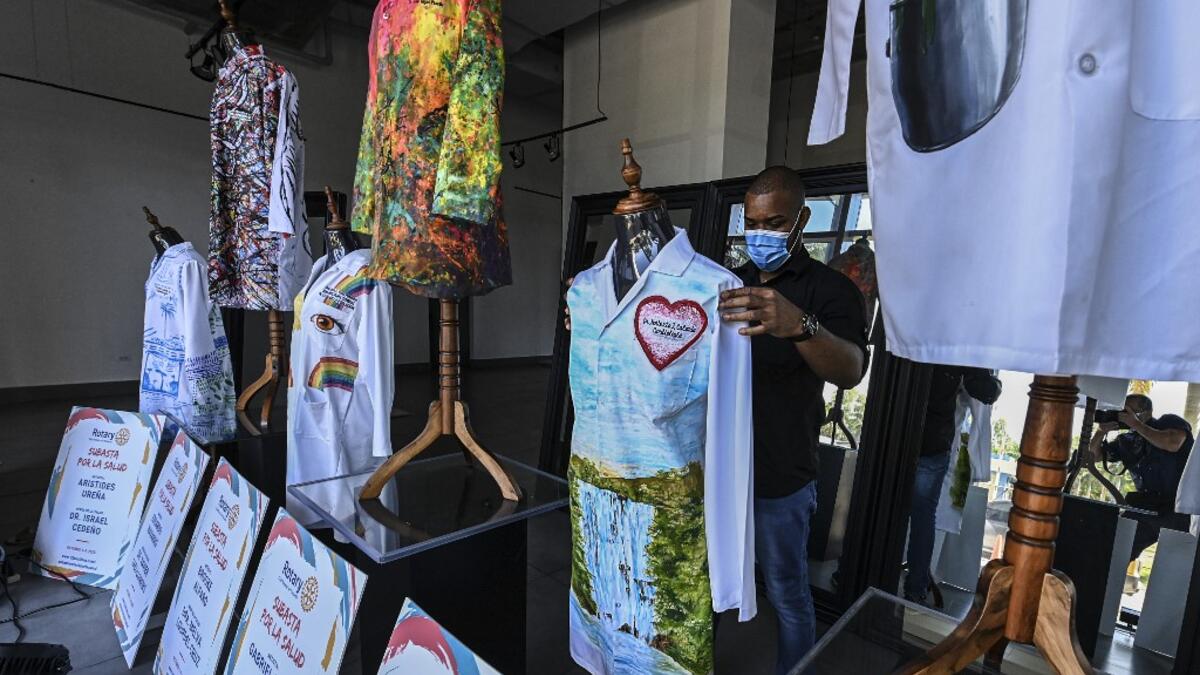 A gallery worker organizes white coats used by doctors fighting against COVID-19 and decorated by Panamanian artists, in Panama City, on September 26, 2020. More than 20 doctor's coats fighting against COVID-19 that were disinfected and painted by Panamanian artists will be auctioned off from October 1 to 4. The funds will go to 20 health centers. Luis ACOSTA / AFP