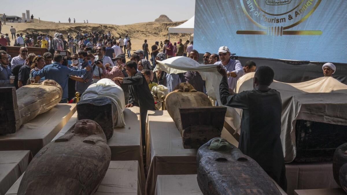 A picture taken on October 3, 2020 shows Egyptian workers covering one of the sarcophaguses, excavated by the Egyptian archaeological mission which resulted in the discovery of a deep burial well with more than 59 human coffins closed for more than 2,500 years, displayed during a press conference at the Saqqara necropolis, 30 kms south of the Egyptian capital Cairo. They were unearthed south of Cairo in the sprawling burial ground of Saqqara, the necropolis of the ancient Egyptian capital of Memphis, a UNES