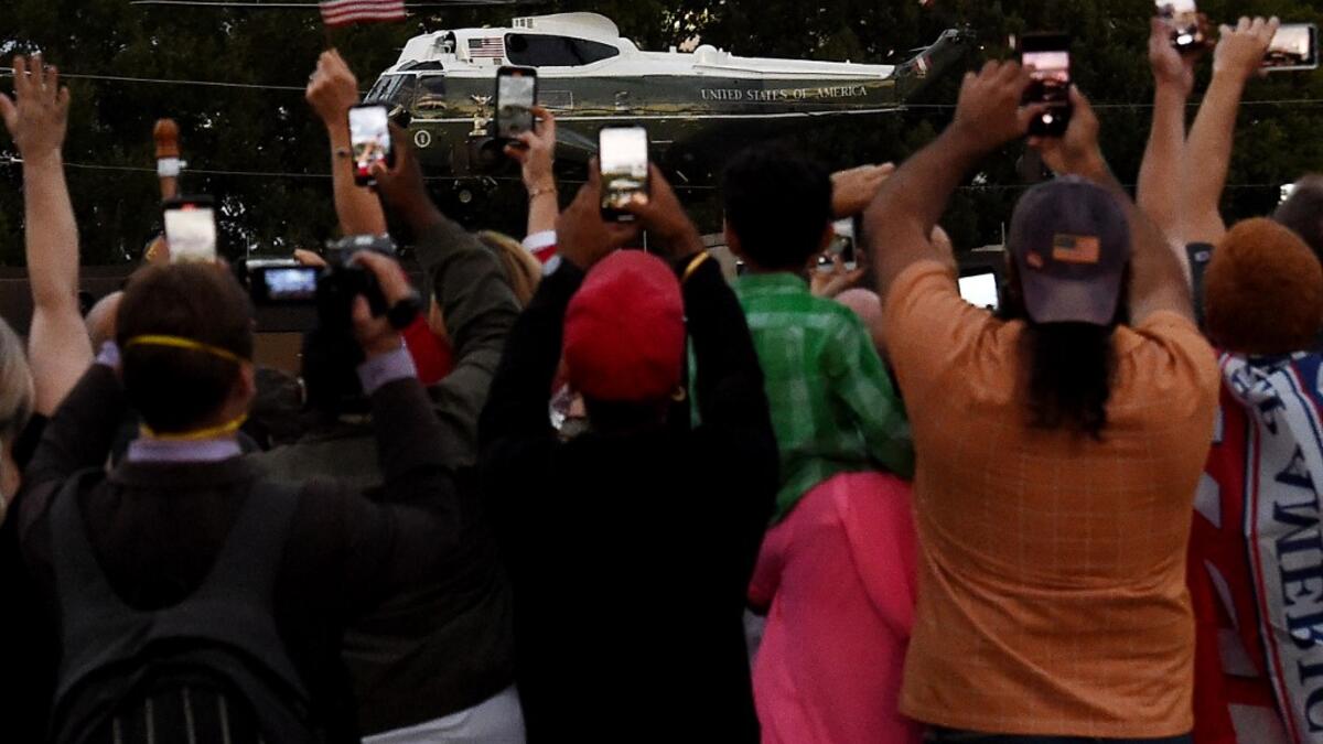 Supporters cheer as US President Donald Trump leaves Walter Reed Medical Center in Bethesda, Maryland on Marine One on October 5, 2020, to return to the White House after being discharged. Trump announced Monday he would be "back on the campaign trail soon", just before returning to the White House from a hospital where he was being treated for Covid-19. Olivier DOULIERY / AFP