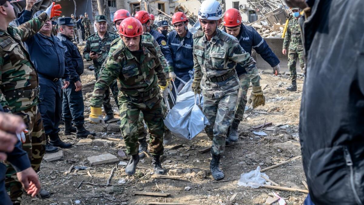 Rescuers carry away the body of a victim at the blast site hit by a rocket during the fighting between Armenia and Azerbaijan over the breakaway region of Nagorno-Karabakh, in the city of Ganja, Azerbaijan, on October 11, 2020. Bulent Kilic / AFP