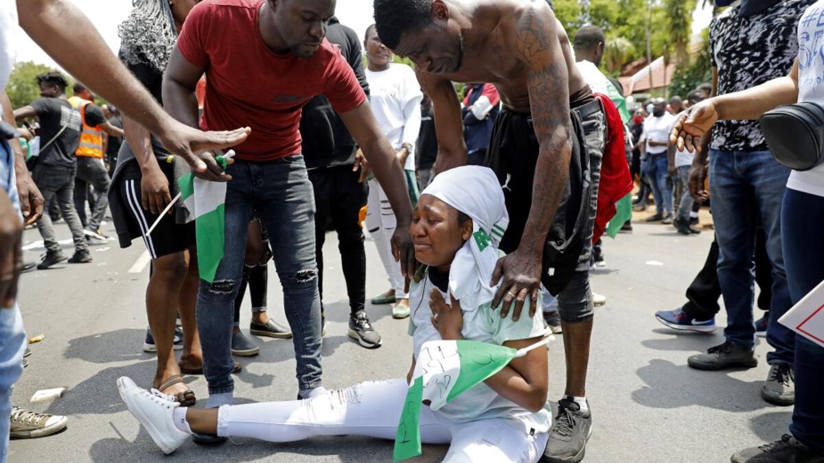 A Nigerian woman based in South Africa weep as others comfort her during a protest outside their embassy in Pretoria on October 21, 2020 in solidarity with Nigerian youth who are demanding an end to police brutality in the form of The Nigerian Police Force Unit, Special Anti-Robbery Squad (SARS). Phill Magakoe / AFP