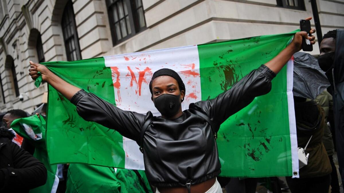 A protester holds a flag stained with fake blood during a demonstration outside the Nigerian High Commission against police brutality in Lagos in London on October 21, 2020. UN Secretary General Antonio Guterres called Wednesday for an end to what he called "brutality" by police in Nigeria, which has been rocked by two weeks of protests. Guterres said gunmen that opened fire on peaceful protesters Tuesday evening in Lagos caused "multiple deaths" and many injuries. Daniel LEAL-OLIVAS / AFP