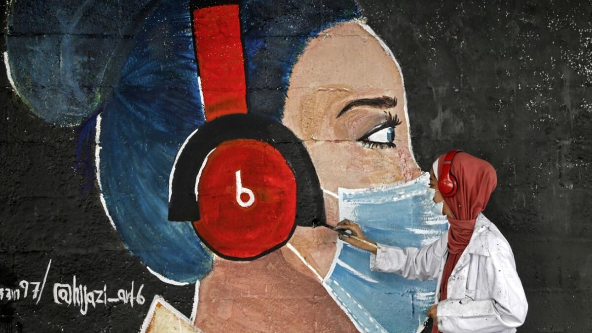 A Palestinian student paints a mural of a mask-clad girl in Gaza City on October 22, 2020, amid the novel coronavirus pandemic crises. Mohammed ABED / AFP
